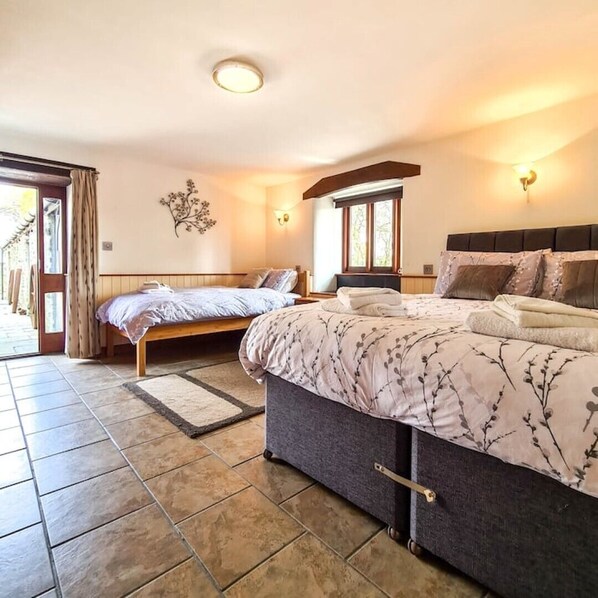 A bedroom with two beds, a large window, and a door leading to an outdoor area. - Ta Mill Dairy Cottage in a Stunning Retreat (Launceston)