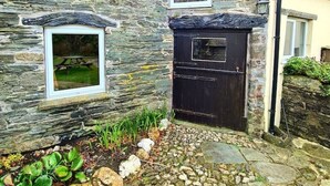 A stone building with a black door and a window above it. - Ta Mill Forge Cottage in a Stunning Retreat (Launceston)