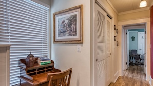 A hallway with a wooden table and chairs, a framed picture on the wall, and a door leading to another room.