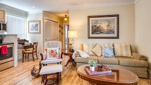 A living room with a sofa, armchair, coffee table, and a painting on the wall.