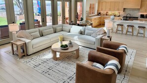 Een ruime woonkamer met een hoekbank, een salontafel en een bruine fauteuil.