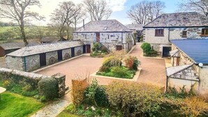 A stone building with a courtyard, surrounded by trees and greenery. - Ta Mill House in a Stunning Retreat (Launceston)