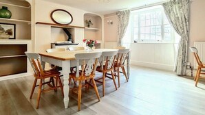 A dining area with a round table and chairs, a chandelier, and a window with curtains. - Ta Mill House in a Stunning Retreat (Launceston)