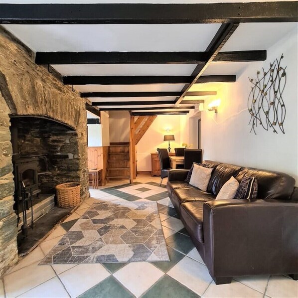A cozy living room with a stone fireplace, a leather sofa, and a checkered floor.