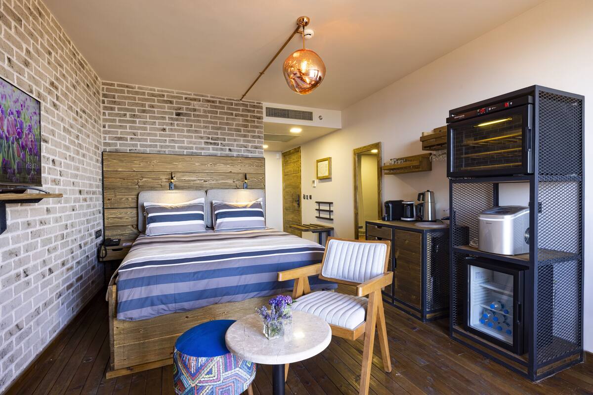 Une chambre d’hôtel de taille réduite, comprenant un lit, une petite table à manger, une chaise, une machine à café et un mini-réfrigérateur.