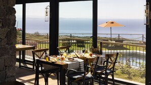 Un coin repas avec une table dressée pour quatre personnes, offrant une vue panoramique sur l’océan.
