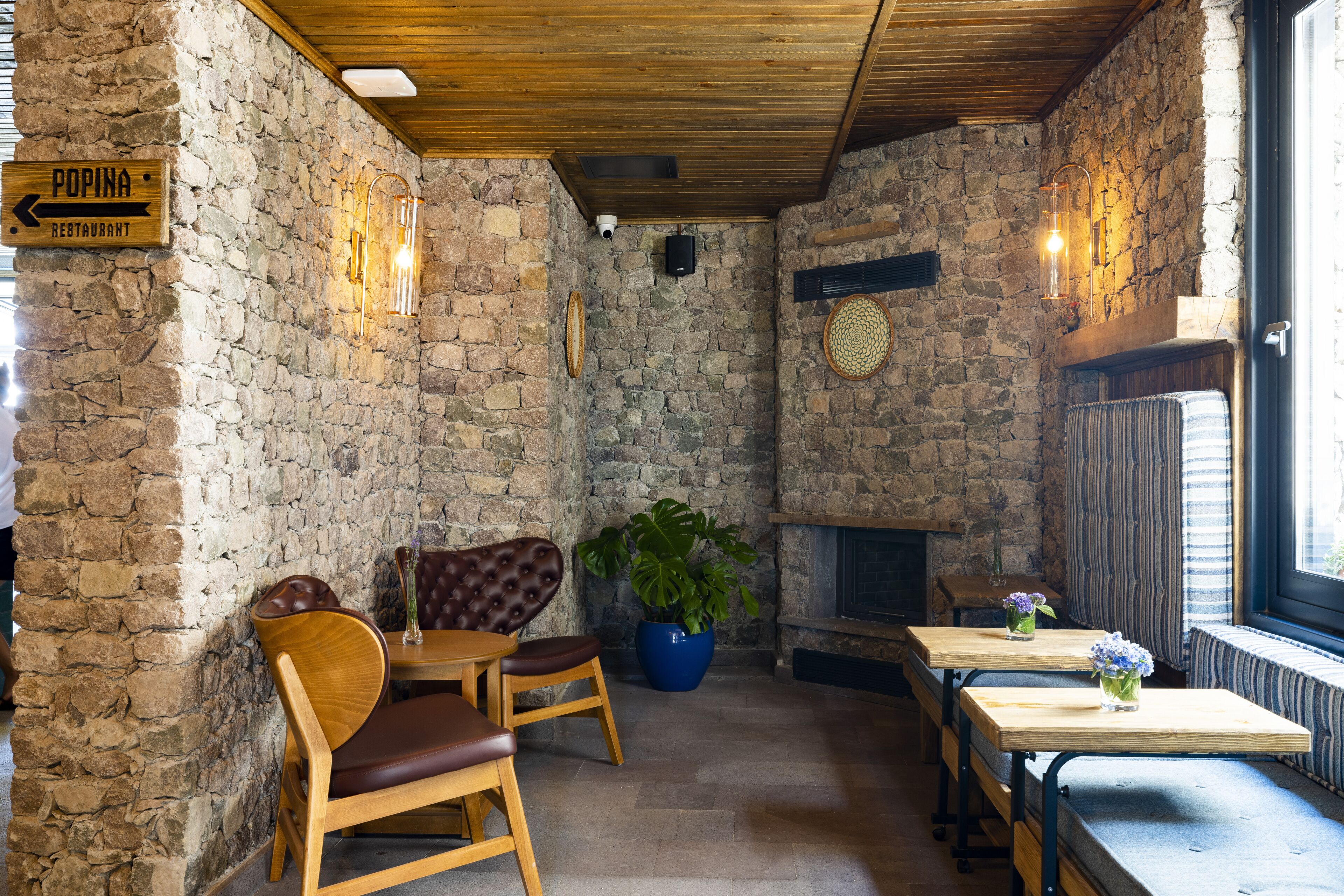 A rustic interior with stone walls, wooden furniture, and a fireplace.