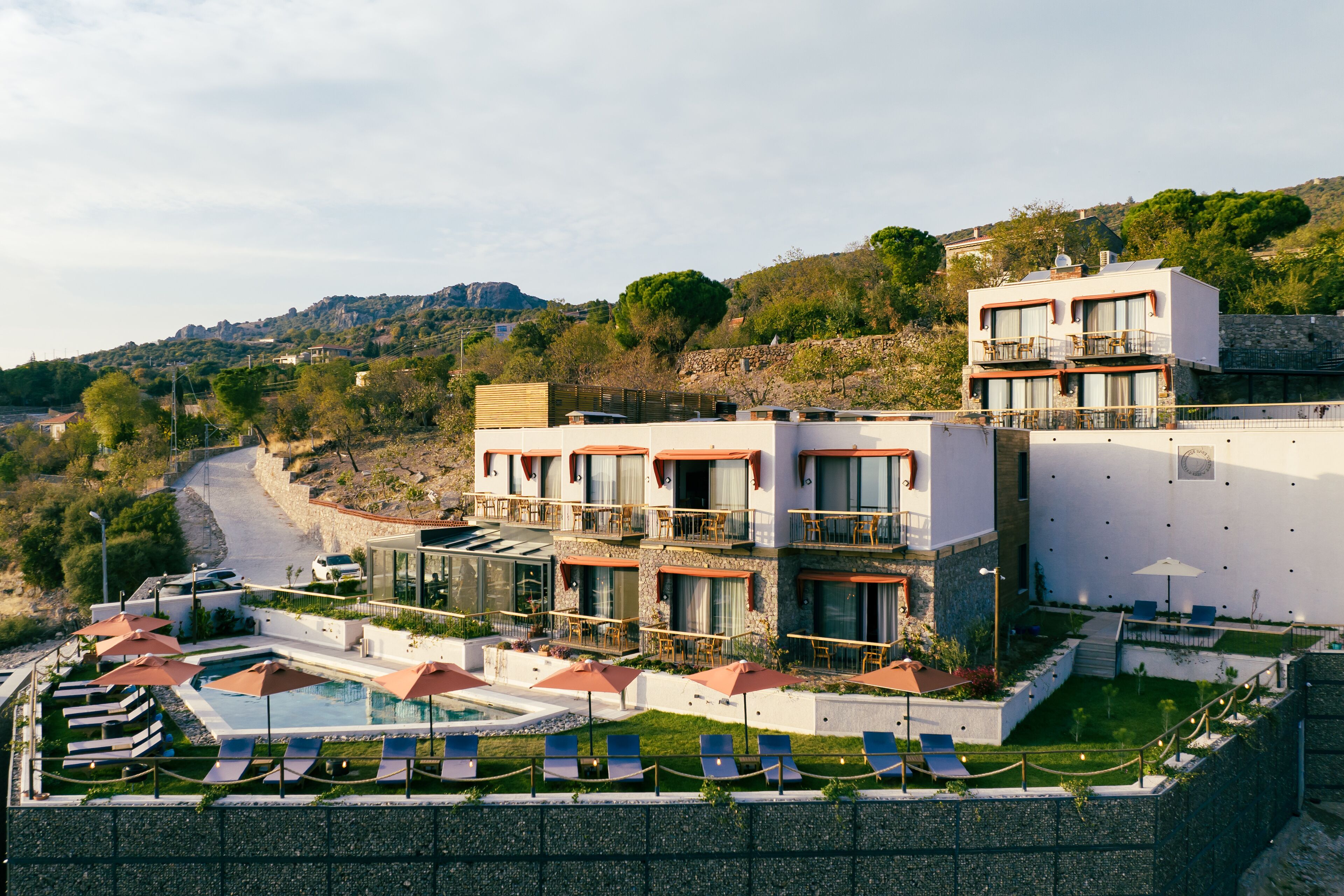 Un hotel moderno con zona de piscina, mobiliario exterior y vistas al paisaje circundante.