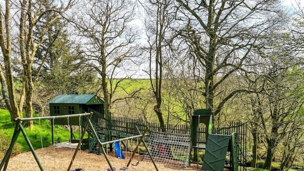 A playground with swings, a slide, and picnic tables.