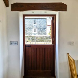 Une porte en bois avec une petite fenêtre, un thermostat et un interrupteur d’éclairage sur le mur.