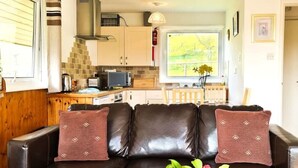 Ein Wohnzimmer mit braun-ledrigem Sofa, einem Holztisch und einer Vase mit Blumen.
