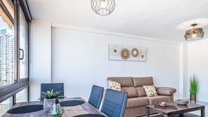 A modern living room with a wooden dining table, blue chairs, a brown sofa, and a coffee table.