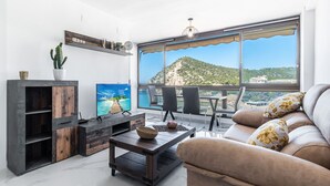A modern living room with a large window, a sofa, a coffee table, and a TV.