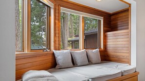 A cozy cabin-style room with a built-in bench seating area, large windows, and wooden paneling.