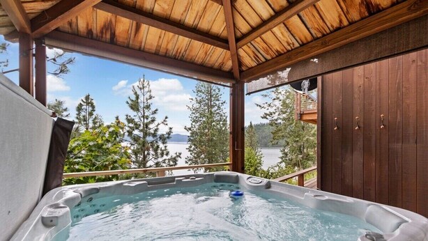A hot tub with a wooden roof and a view of trees and water.