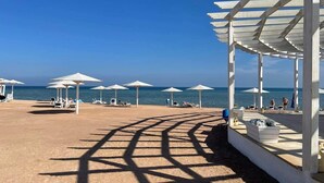 Ein Strand mit weißen Sonnenschirmen und Liegestühlen.