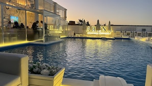 Ein Poolbereich mit Liegestühlen, einem Restaurant und einer Bar mit Blick auf den Pool.