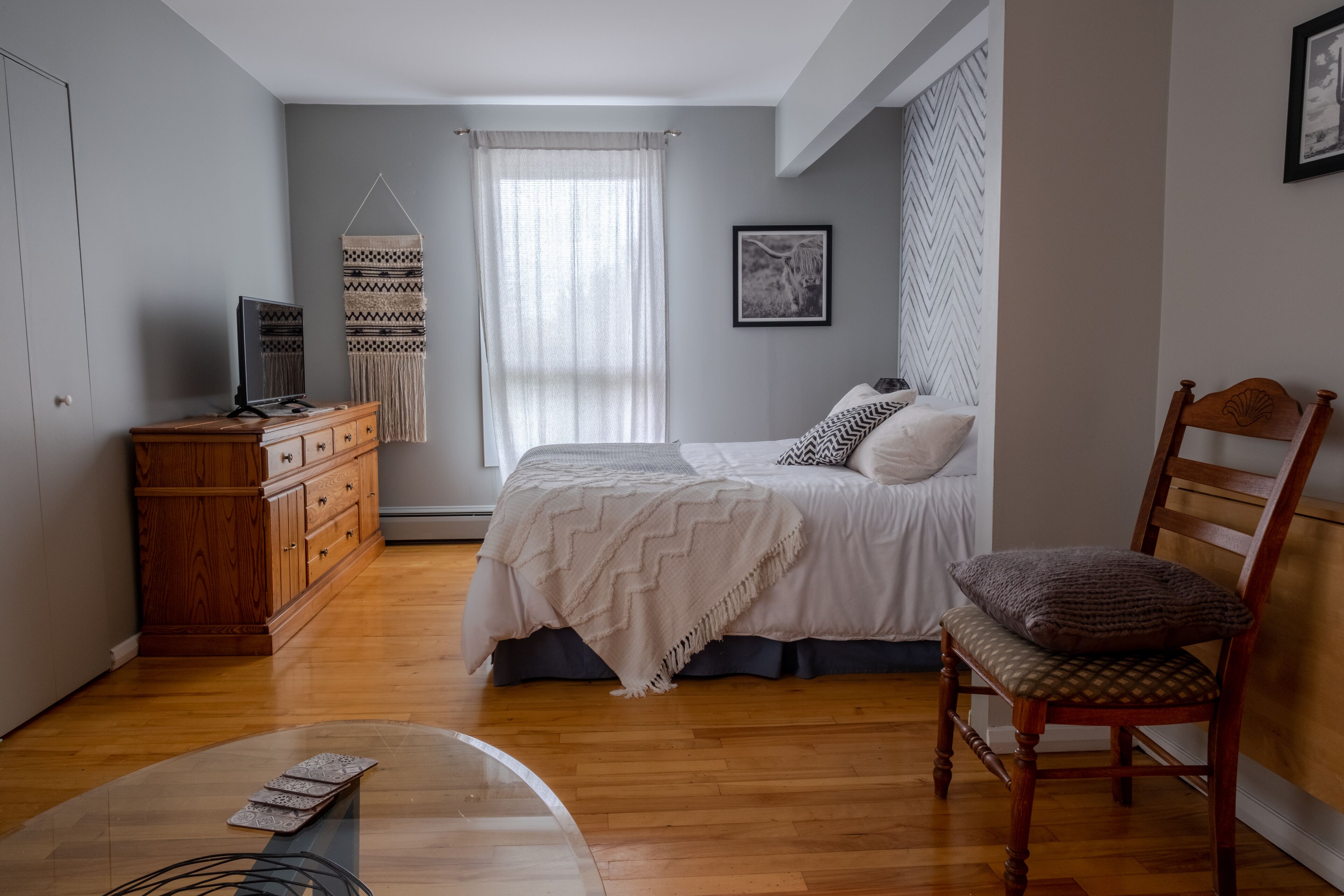 Une chambre à coucher avec un lit, une commode en bois et une chaise.