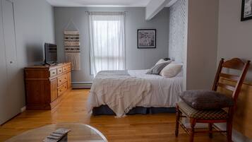 Une chambre à coucher avec un lit, une commode en bois et une chaise.