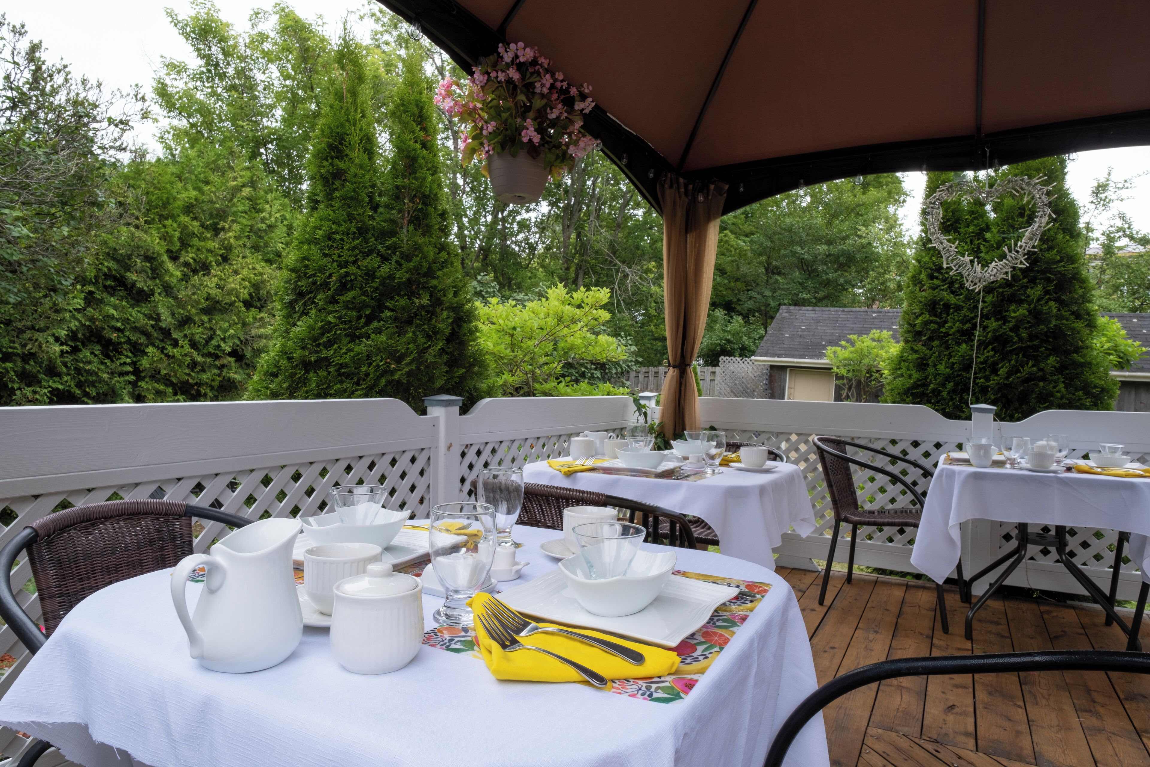 Une terrasse extérieure avec des tables disposées pour les repas, entourée de verdure.