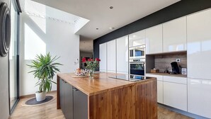 Una cocina moderna con una isla de madera, hornos empotrados y un amplio ventanal que proporciona luz natural.