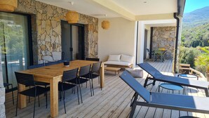 Una terraza de madera con una mesa de comedor y sillas, un sofá y sillones.
