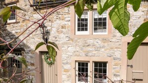 Un bâtiment en pierre avec un banc en bois et une plante suspendue.