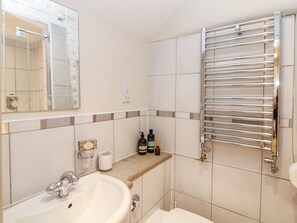 Une salle de bain équipée d’un lavabo, d’un miroir, d’un porte-serviettes et d’articles de toilette.