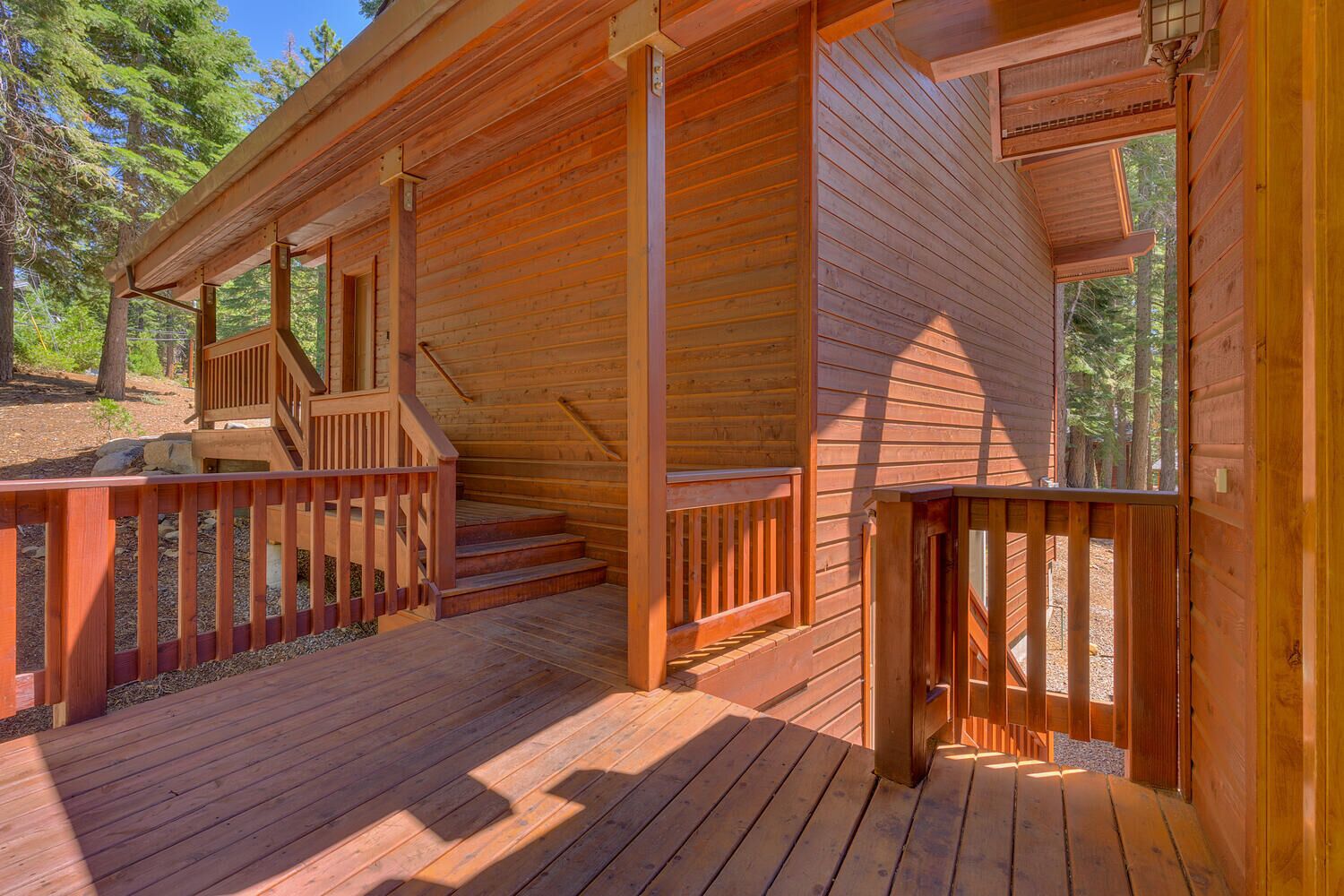 Une cabane en bois dotée d’un porche couvert, d’un escalier et d’une terrasse.