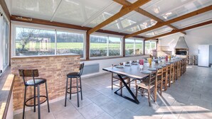 A spacious kitchen with a long counter, ample natural light from large windows, and a brick wall. - So Villa Noé Michel (72) - Heated pool - Basketball - 2h Paris - 30 p. (Vallon-sur-Gée)