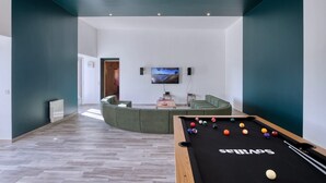 A modern living room with a pool table, a green sofa, and a TV mounted on the wall. - So Villa Noé Michel (72) - Heated pool - Basketball - 2h Paris - 30 p. (Vallon-sur-Gée)