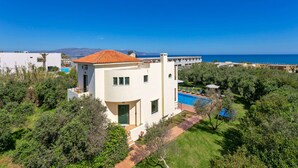 A modern villa with a pool, surrounded by lush greenery and a clear blue sky. - Villa Ilos by Villa Plus (Pyrgos Psilonerou)