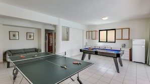 Une pièce équipée d’une table de ping-pong, d’un billard, d’un canapé et d’un coin cuisine.