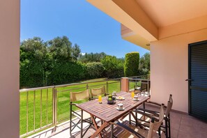 Ein Balkon mit Tisch für zwei Personen, mit Blick auf einen gepflegten Garten und Bäume.