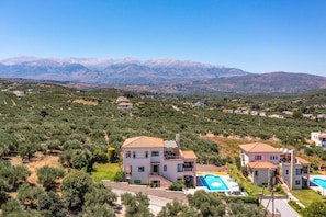 Un quartier résidentiel avec une grande maison à deux étages, dotée d’une piscine et offrant une vue sur les montagnes lointaines.