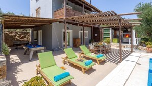 Un edificio de dos pisos con piscina, zona de estar al aire libre y una barbacoa.
