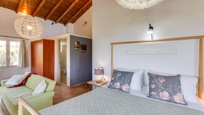 Un dormitorio con una cama, un sofá verde, techo de madera y una lámpara decorativa.