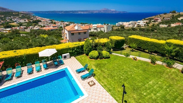 A pool area with a view of the sea and a residential neighborhood.