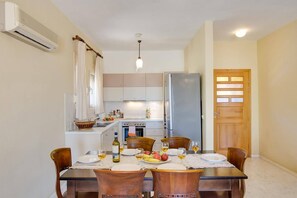 Un coin repas avec une table dressée pour quatre personnes, une cuisine en arrière-plan et une porte en bois.