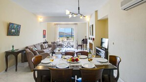 Un coin repas avec une table dressée pour quatre personnes, un canapé et un téléviseur en arrière-plan.
