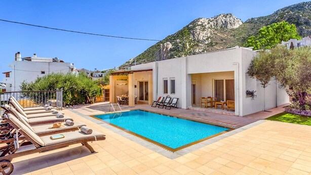 Une villa moderne dotée d’une piscine, d’un espace salon extérieur et offrant une vue sur les montagnes.