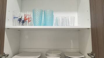 A kitchen cabinet with shelves holding glassware and plates.
