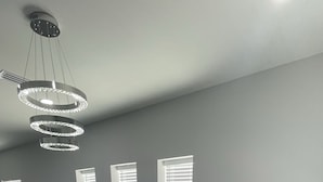 Un saló modern amb un sofà gris, un butaques negre de cuir, una taula de centre i un penjador.