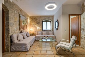 A living room with a stone wall, a sofa, a glass coffee table, and a reclining chair.