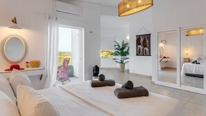 A modern bedroom with a large bed, a sitting area, a large mirror, and a view of the outdoors. - Villa Monroe by Villa Plus (Hersonissos)