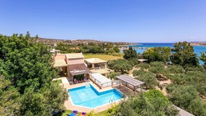 A residential property with a swimming pool, outdoor seating, and a view of the sea. - Villa Olive Grove by Villa Plus (Marathi)