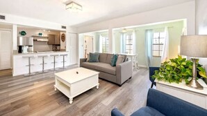 Una sala de estar amplia con sofá, mesa de centro y comedor con barra.
