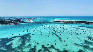 Vista aérea de una zona costera con un puente, aguas turquesas cristalinas y numerosos barcos.