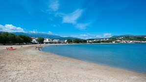 A beach with clear blue water, a sandy shore, and buildings in the background. - Villa Potami Angela by Villa Plus (Apokoronos)