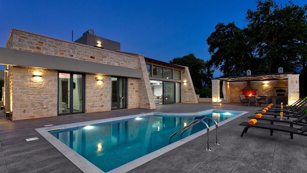 A modern house with a swimming pool, outdoor seating, and a stone fireplace. - Villa Potami Angela by Villa Plus (Apokoronos)